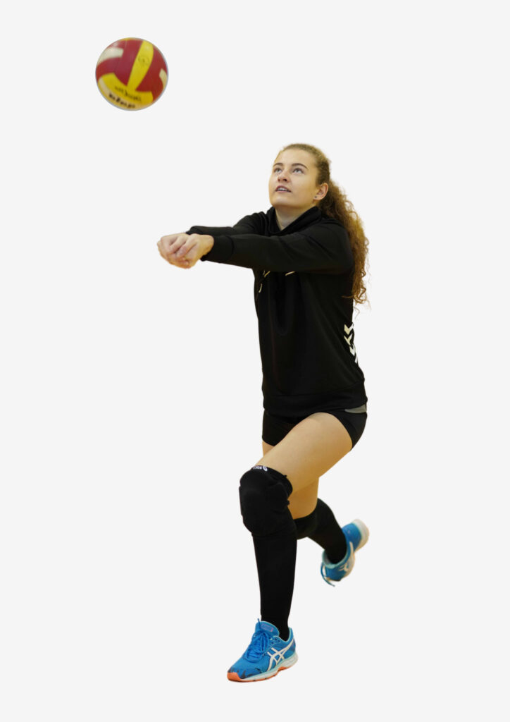 A girl with blonde hair and black KTU sportswear hits a volleyball