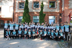 Kaunas university of technology sports team players standing in three rows in front of red bricks building outside.
