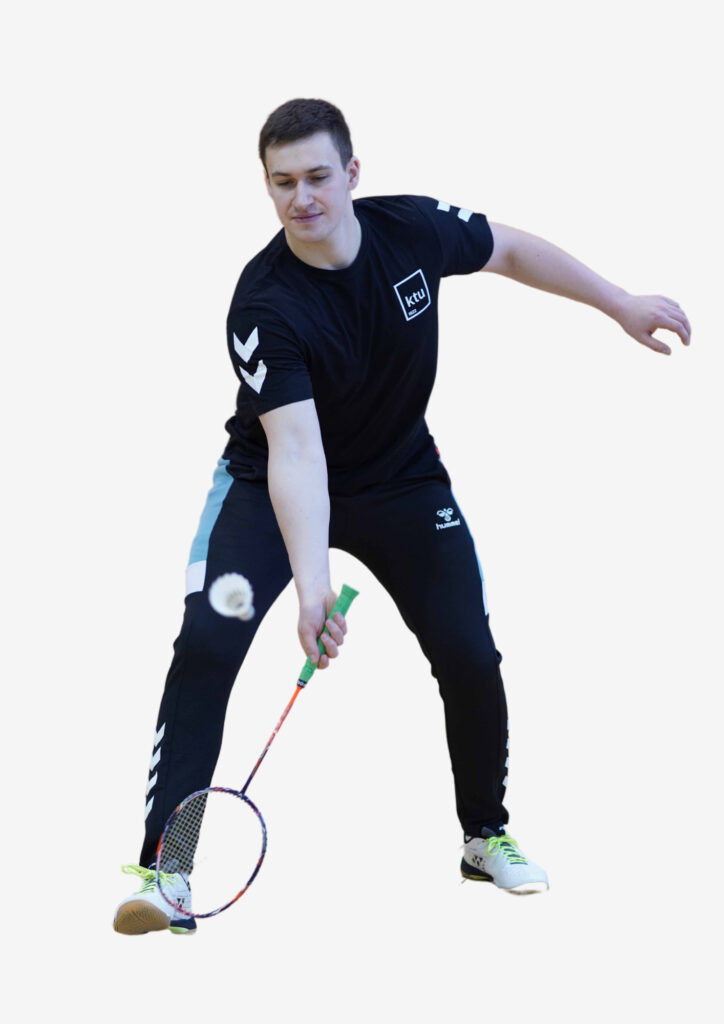 A guy with dark hair and black KTU sportswear hits a badminton ball with a racket