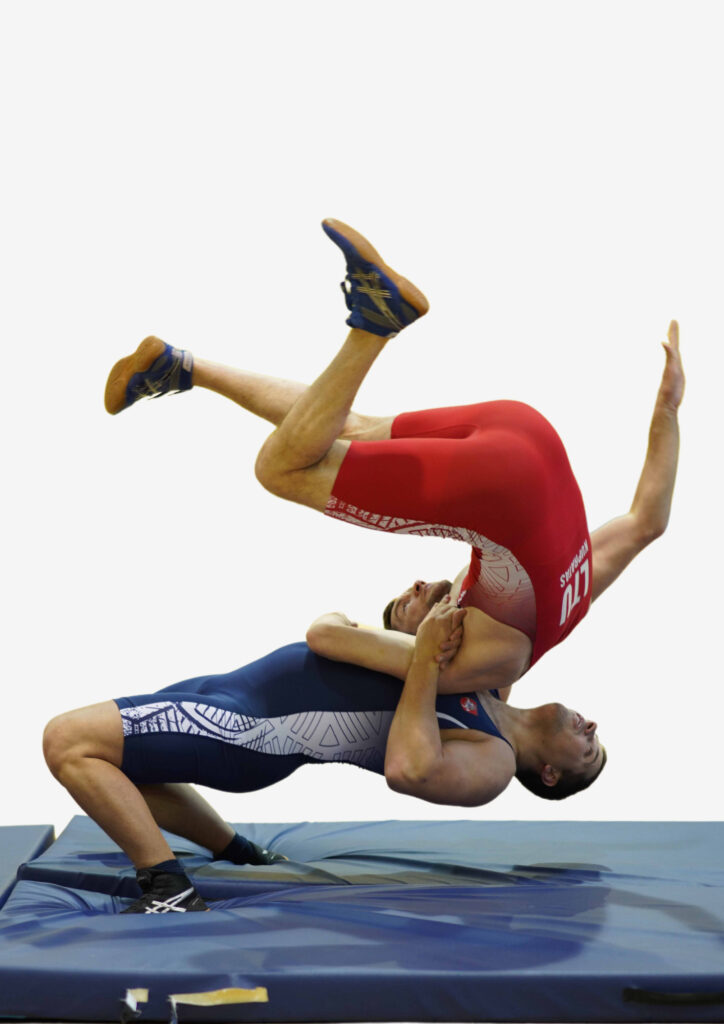 Two men inred and blue sports clothes performing wrestling action 